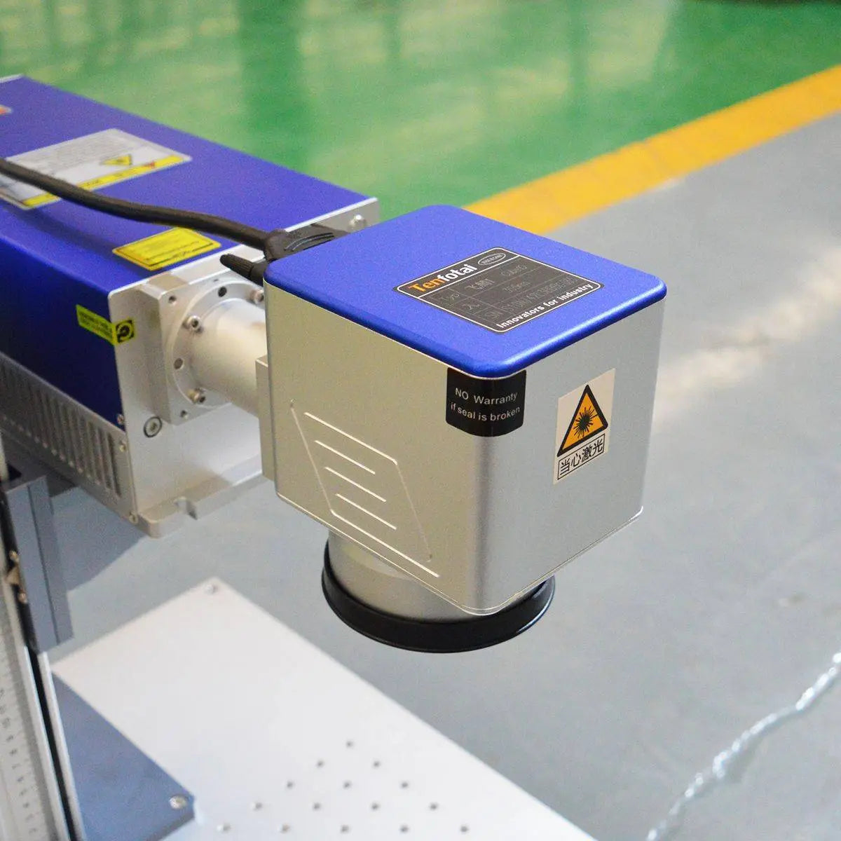 Close-up of avalaser UV laser head with safety warning labels, showcasing the precision optics used for fine engraving on various materials.
