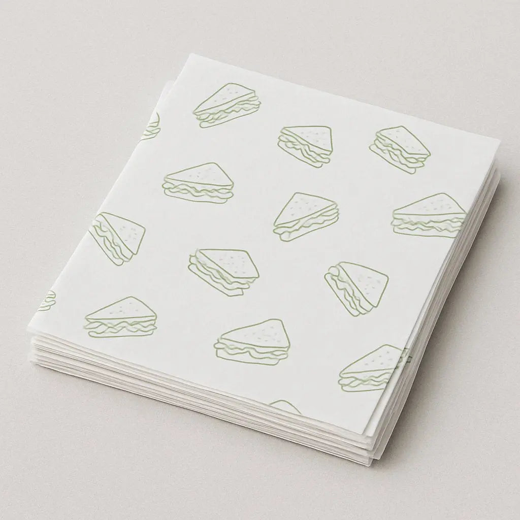 Stack of white sandwich wrapping paper with green food illustrations – part of Printava’s custom food packaging collection.