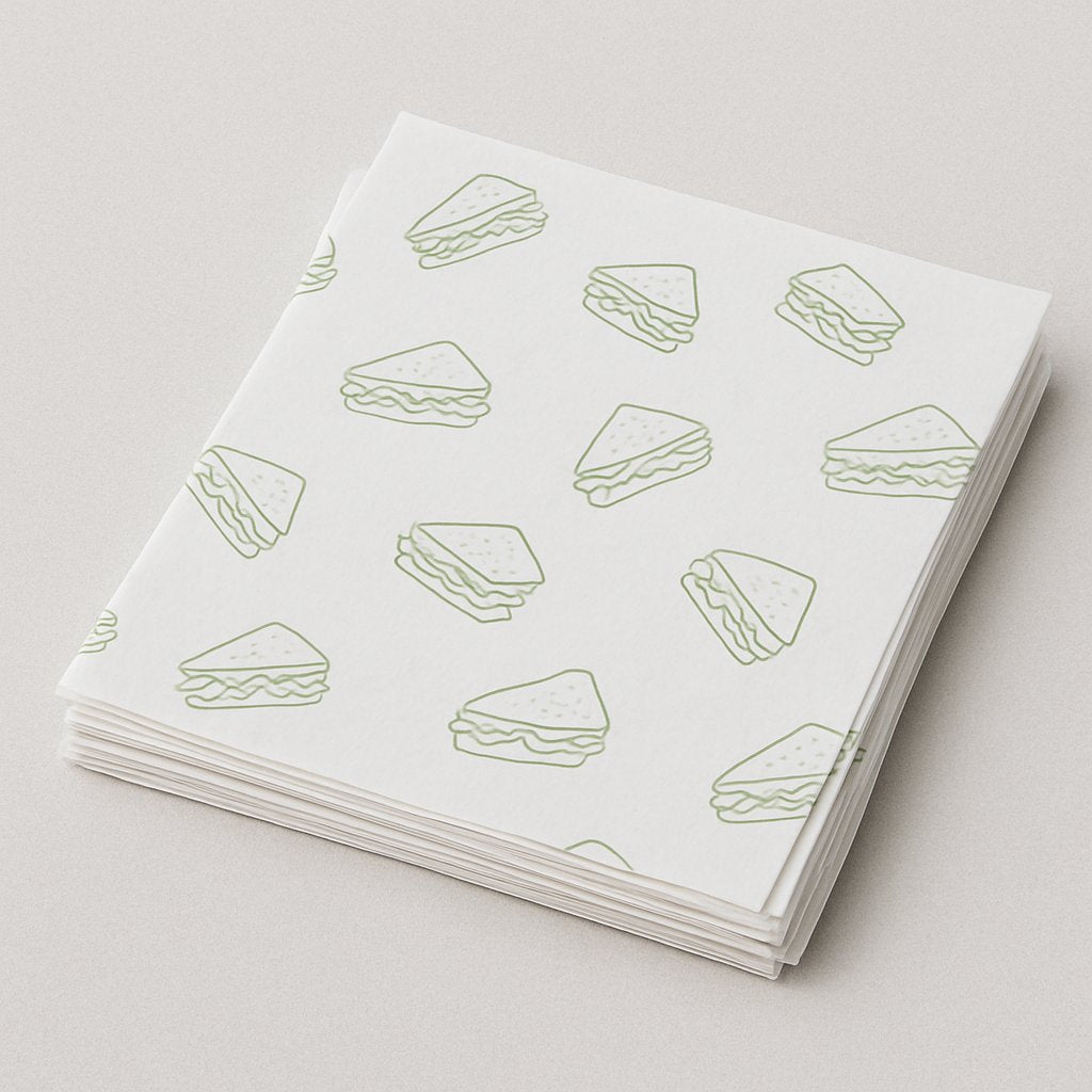 Stack of white sandwich wrapping paper with green food illustrations – part of Printava’s custom food packaging collection.
